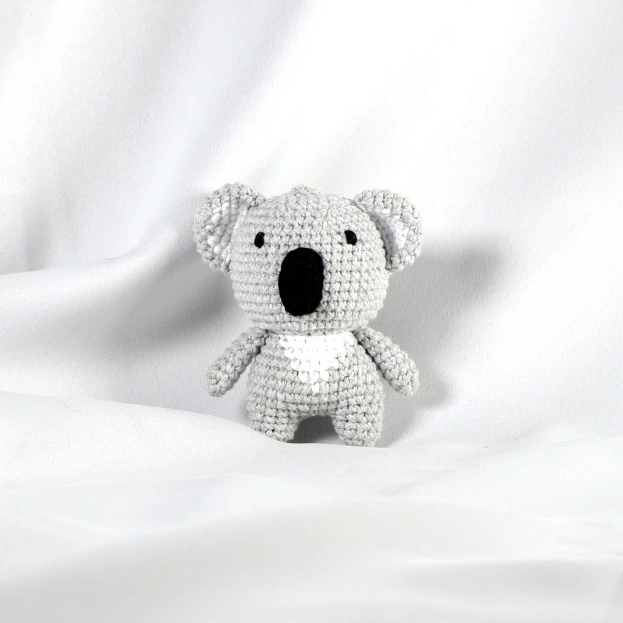 Crocheted grey koala toy on a white background