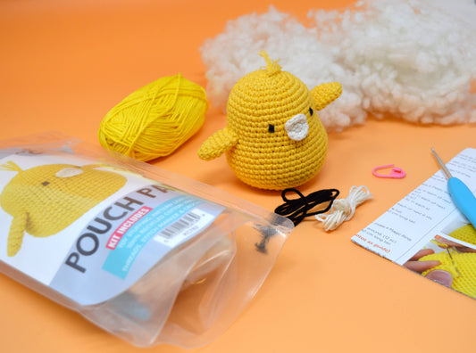 Yellow crochet chick toy with yarn, tools, and instructions on an orange background